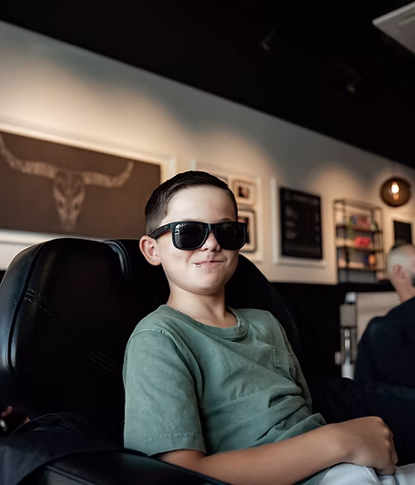A young client in sunglasses waiting in the barber chair